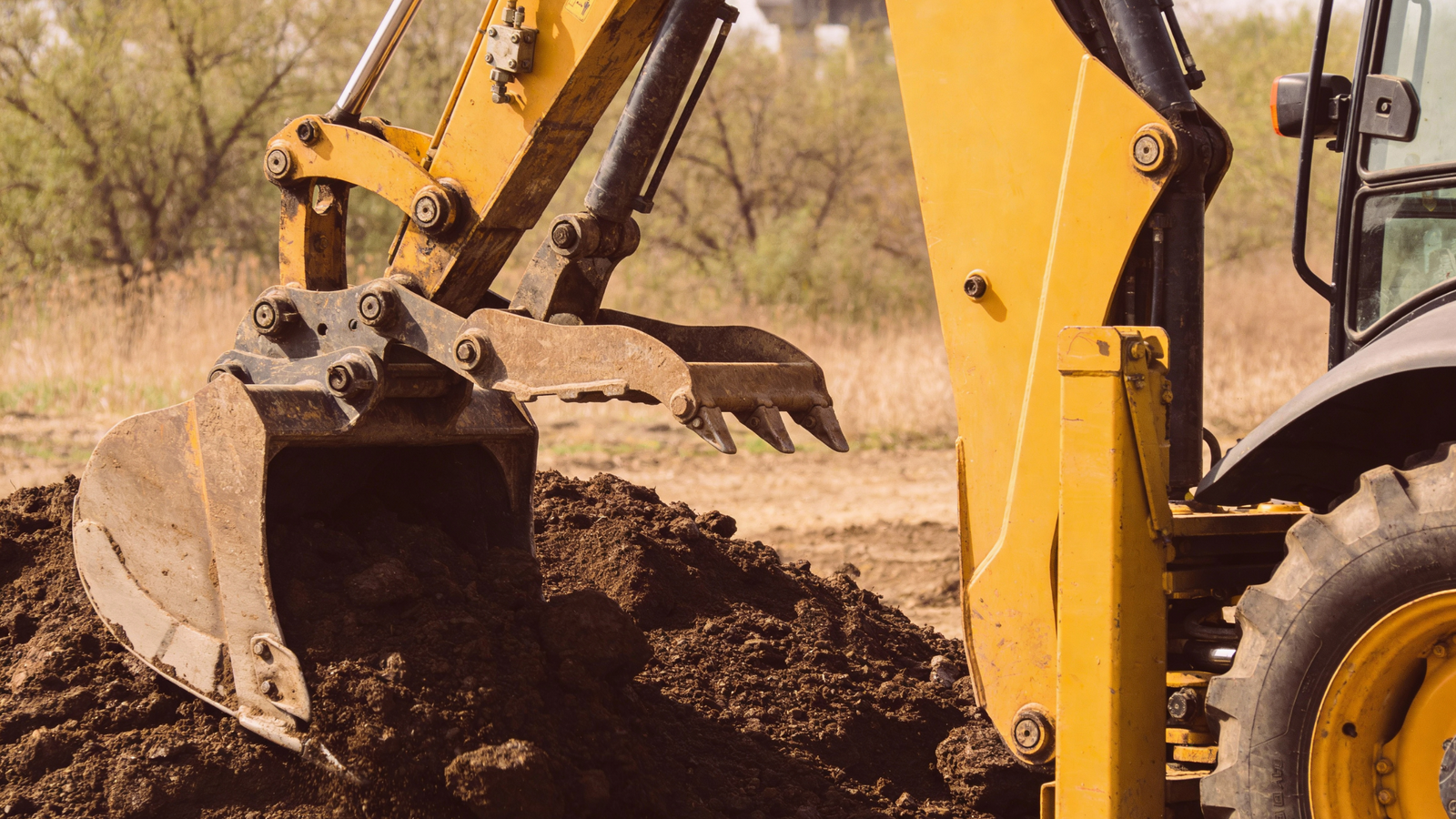 Drain Bros llc installs a septic system, using equipment to move soil and prepare the area for construction work.