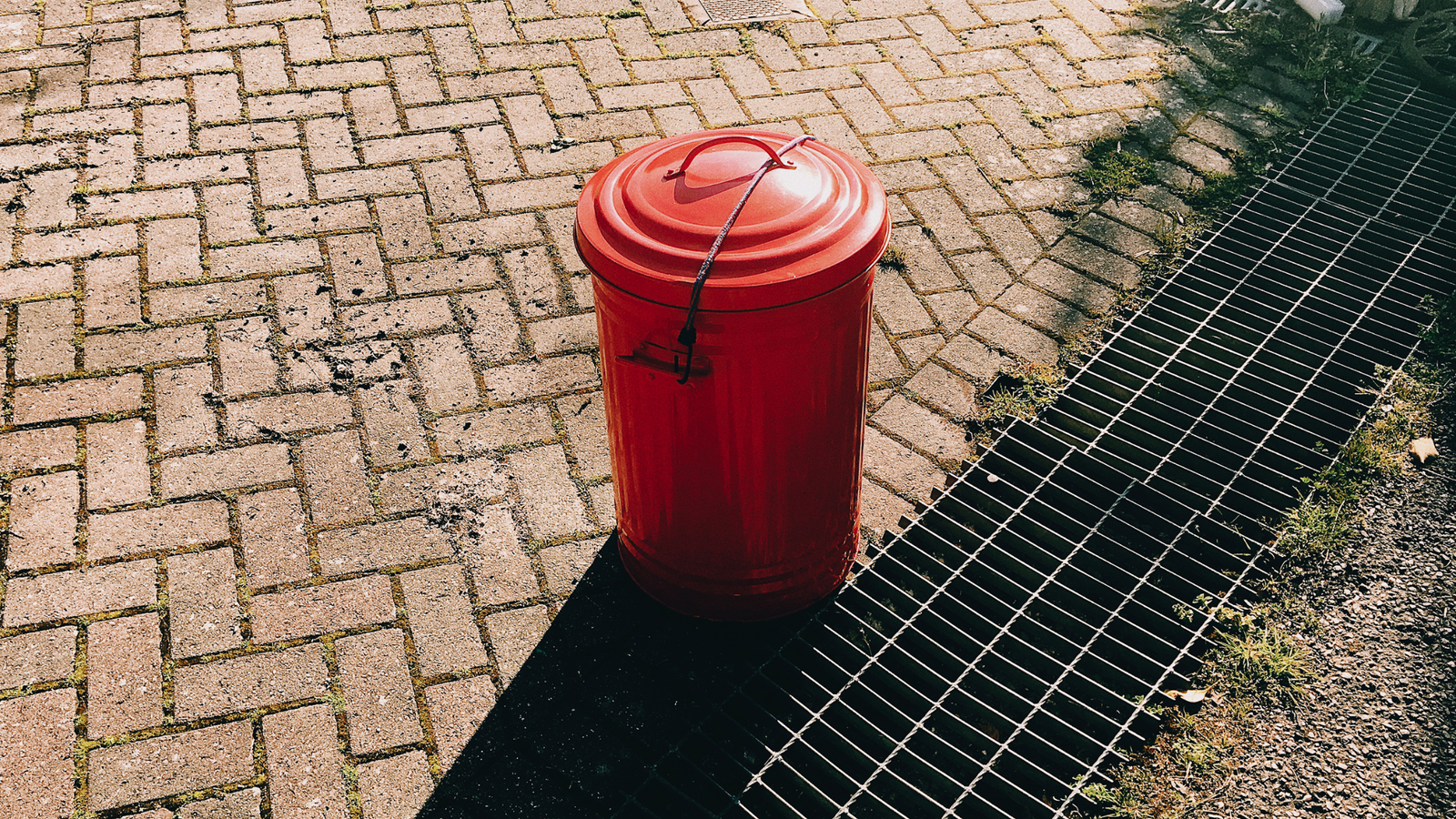 Drain Bros llc shows a new drainage system beside a trash bin, suggesting recent improvements to the walkway area.