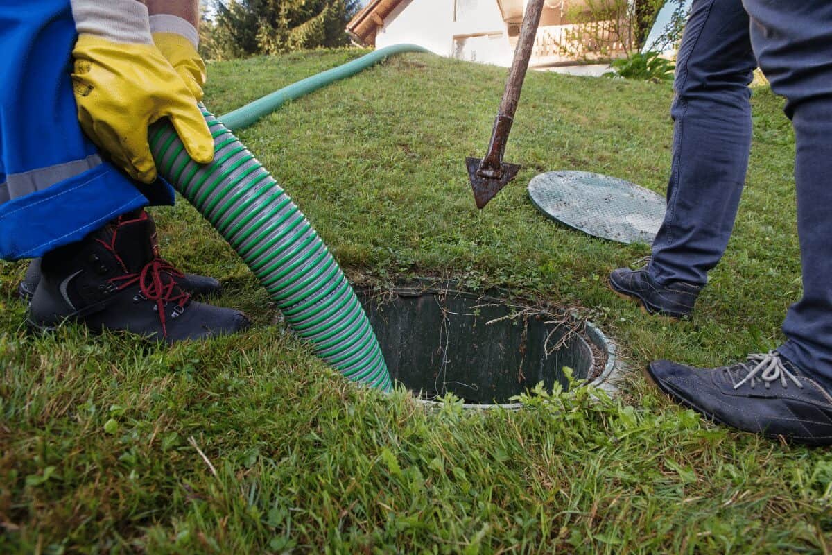 Drain Bros llc team works on a septic tank, showing professional help for sewer or septic system issues in a yard.