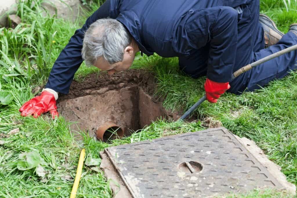 Drain Bros llc worker checks a drain, showing sewer repair services and careful inspection in action.