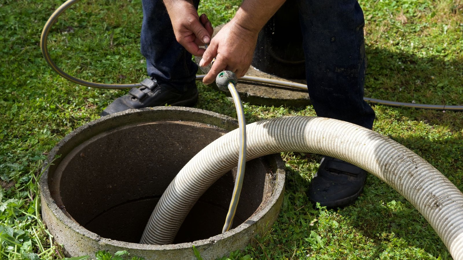 Drain Bros llc worker cleans and maintains an outdoor septic tank after emergency sewer repair.