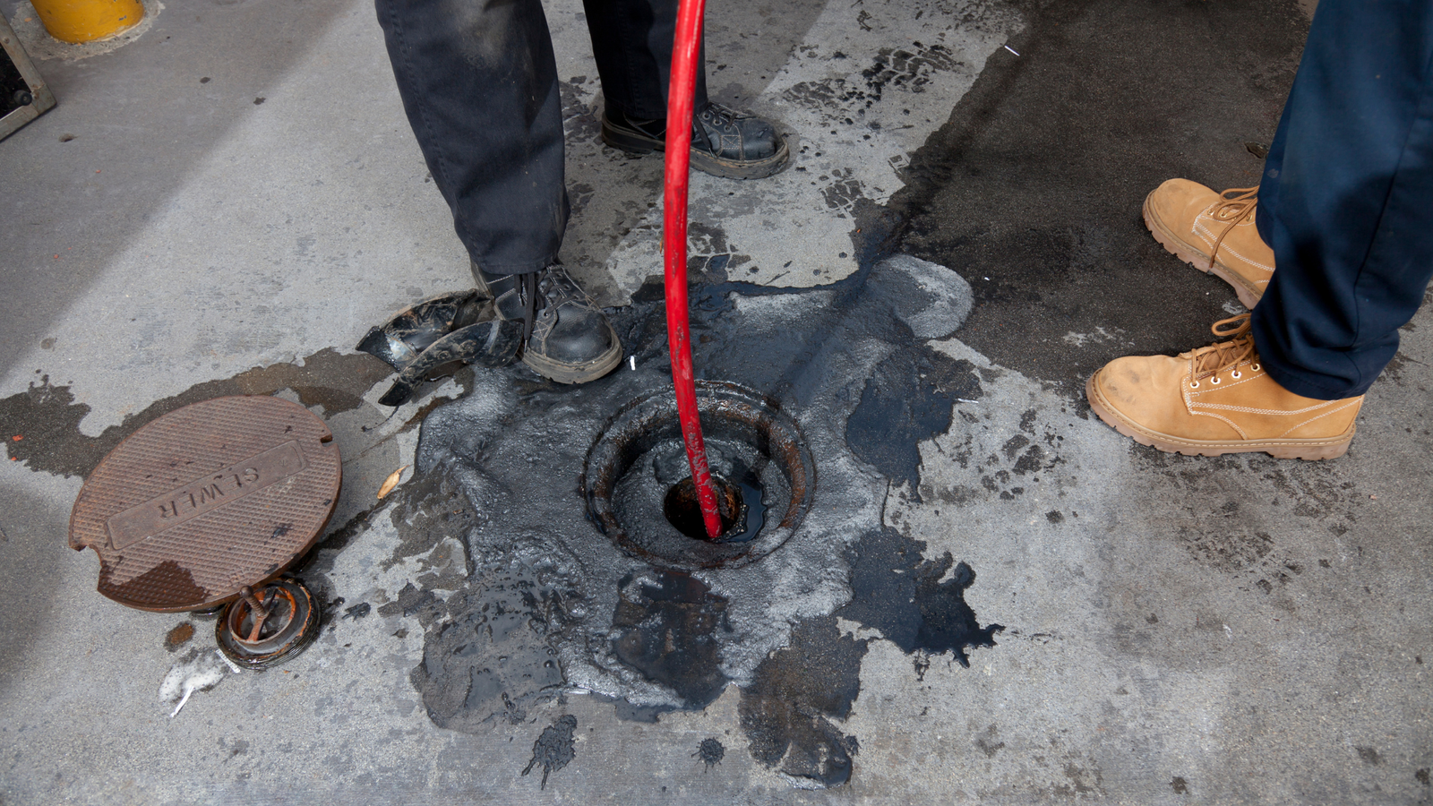Drain Bros llc team fixes a sewer emergency, cleaning up a black liquid spill and working safely to solve the problem.