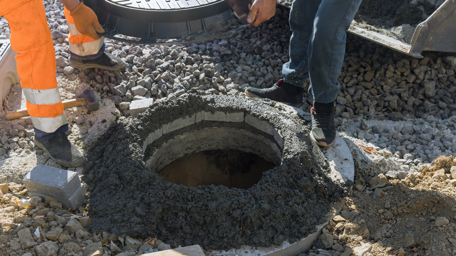 Drain Bros llc workers fix a manhole cover as part of a home excavation project to improve safety and access.