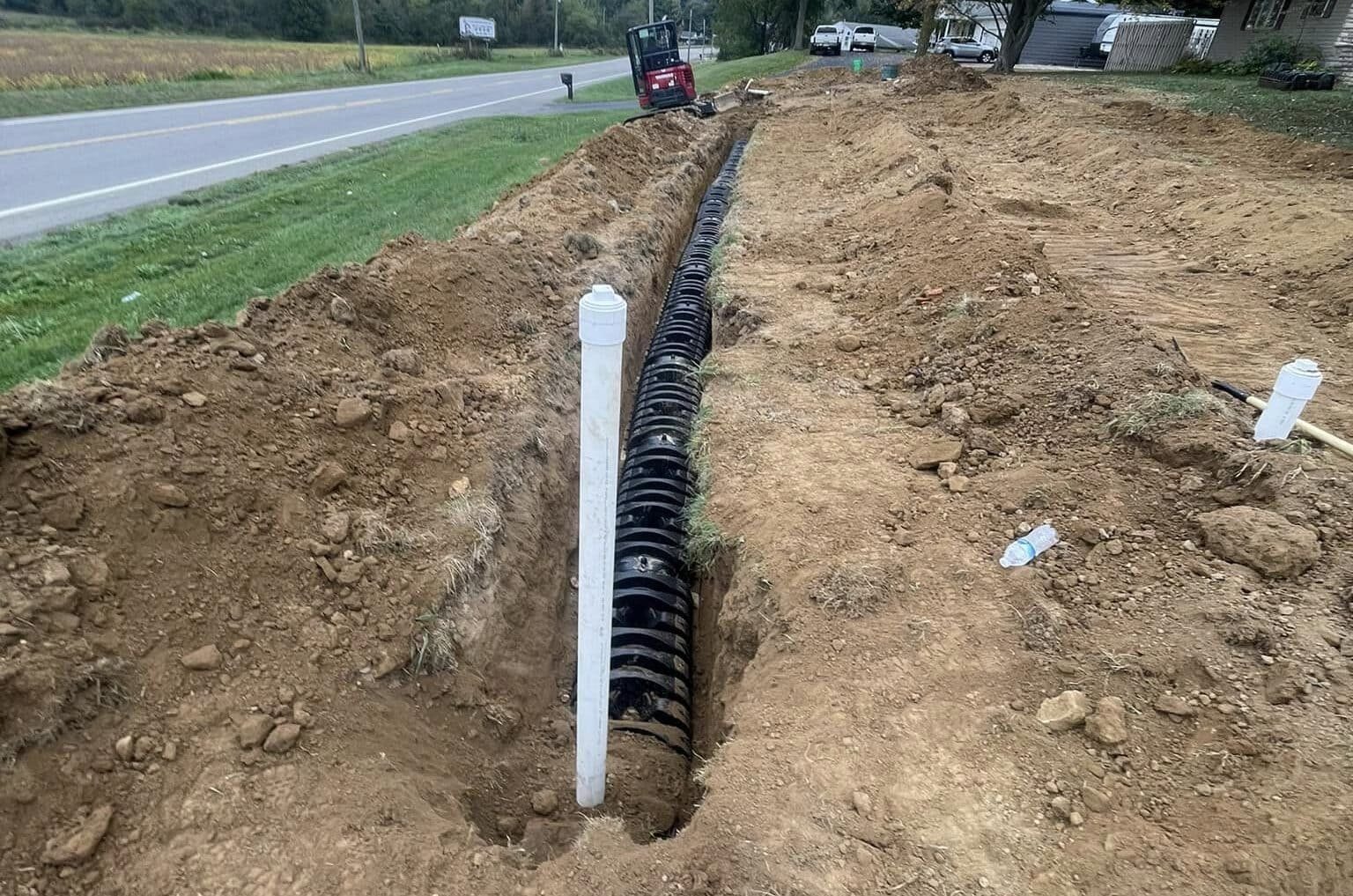 Drain Bros llc works on a home excavation project, installing drainage pipes for better water control in a yard.