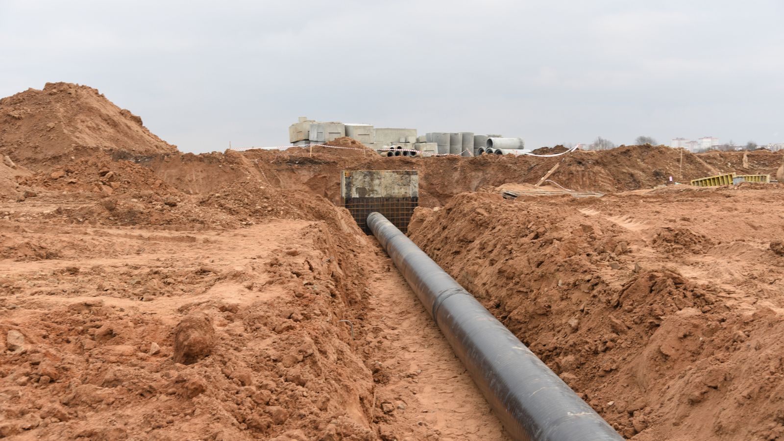 Drain Bros llc working on pipe installation in a trench, showing progress and teamwork at a busy construction site.