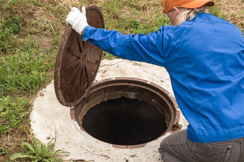 A Drain Bros llc worker checks a manhole to look for any possible sewer or pipe issues at a home.