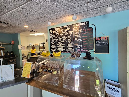 Drain Bros llc signs in a bakery show they install septic systems while staff work behind the counter serving pastries.