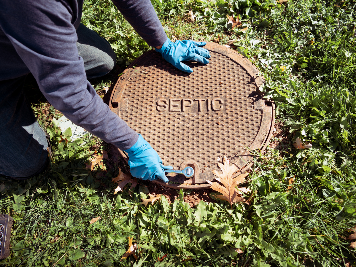 A Drain Bros llc worker checks a septic tank for problems, showing expert care and maintenance of home sewer systems.