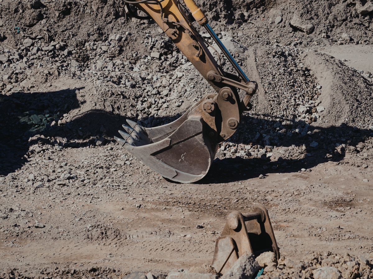 Drain Bros llc using excavation tools to prepare ground for drainage or septic system installation at a work site.