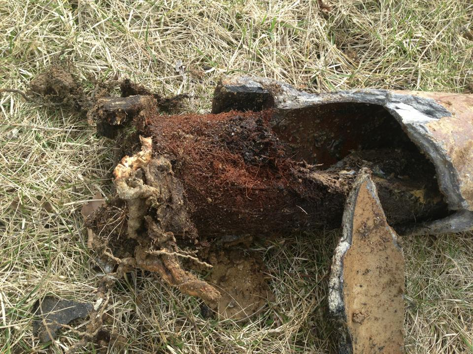 Drain Bros llc shows a damaged metal pipe needing sewer repair, with rust and debris showing it has serious issues.
